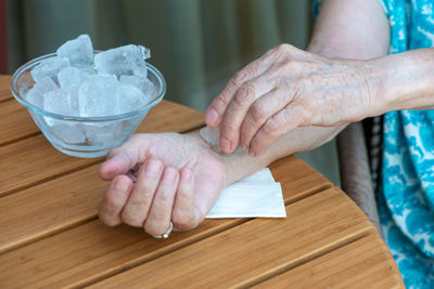 Senior woman holds ice cube on her wrist. how to stay cool in hot weather. beat the heat. 