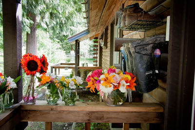 Flowers in glass vases on wooden railing by shoe rack