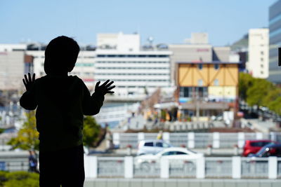 Rear view of silhouette boy standing in city