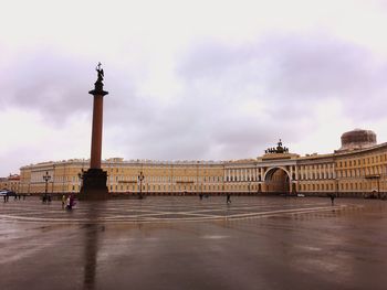 Statue in city against cloudy sky