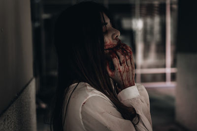 Side view of young woman with halloween make-up against wall