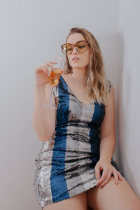 Young woman holding champagne flute against gray background