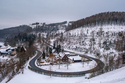 Snow covered trees and buildings against sky