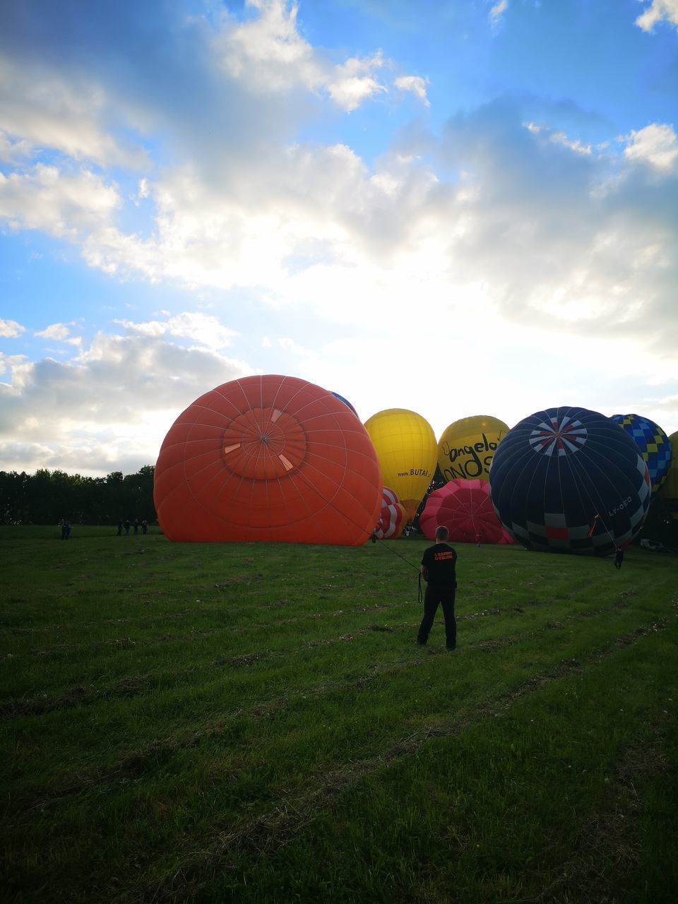 PEOPLE STANDING ON FIELD AGAINST ORANGE SKY