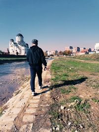 Rear view of man standing on building against sky