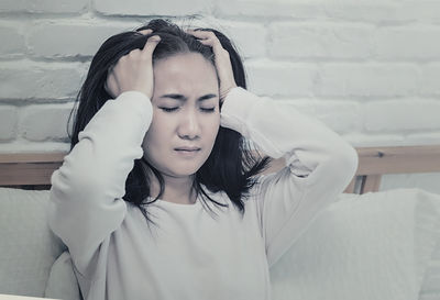 Portrait of young woman with eyes closed against wall