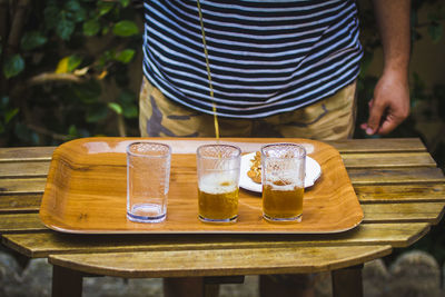 Midsection of man holding drink served on table