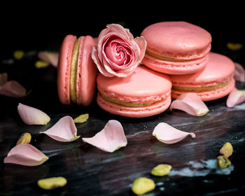 Pink pistachio rose macarons against a black background