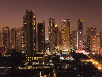 Illuminated buildings in city against sky at night