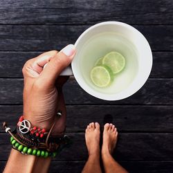 Woman's hand holding cup with water and lime