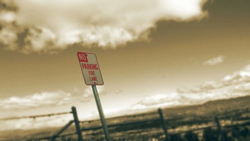 Road sign against cloudy sky