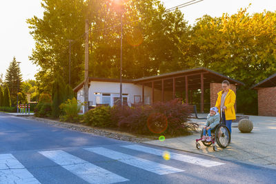 Mother pushing wheelchair with her daughter, girl living with cerebral palsy, crossing the road.