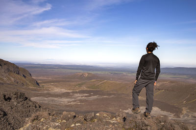 Rear view of man standing on mountain against sky