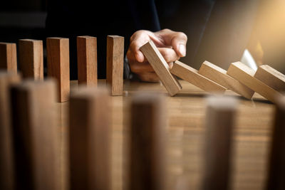 Cropped hand playing with wooden dominoes on table