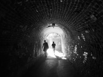 Silhouette people walking in tunnel