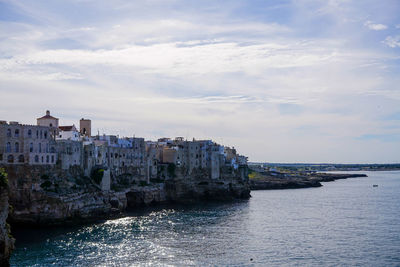 Residential district by sea against cloudy sky