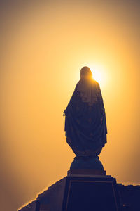 Low angle view of statue against orange sky