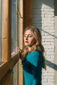 Portrait of young woman looking through window