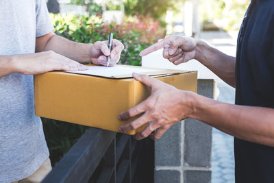 Midsection of delivery man pointing at signing sheet