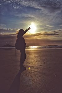 Silhouette woman standing at beach during sunset