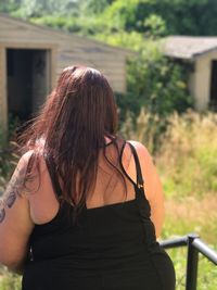 Rear view of woman with long hair standing at yard