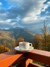 Coffee on table by mountains against sky