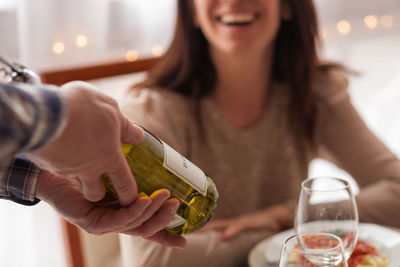 Close-up of man holding drink with woman sitting on table at home