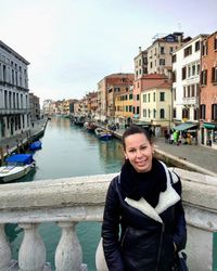 Portrait of smiling woman standing on canal in city