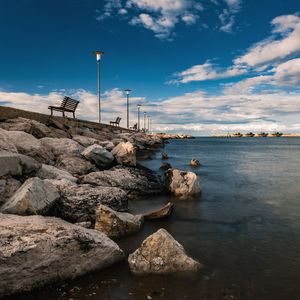 Rocks on shore by sea against sky