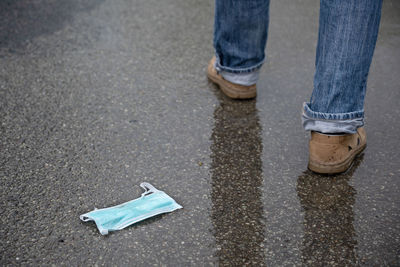 Low section of man walking on wet road