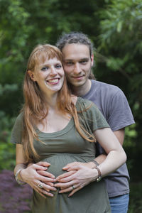 Portrait of happy pregnant woman standing with man