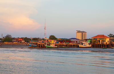 Buildings by sea against sky during sunset