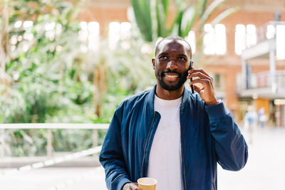 Young stylish afro american male in modern station speaking on mobile phone