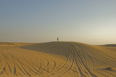 Tire tracks in desert against clear sky