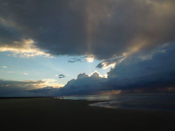 Scenic view of beach against cloudy sky