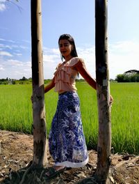 Portrait of smiling mid adult woman standing amidst tree trunks at farm