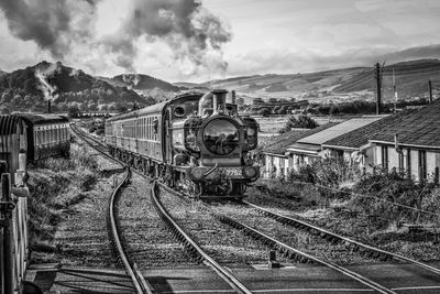 Train on railroad track against sky and rolling hills 