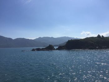 Scenic view of sea and mountains against blue sky