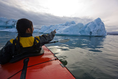 Woman rowing sea kayak on jökulsárlón glacier lagoon in iceland