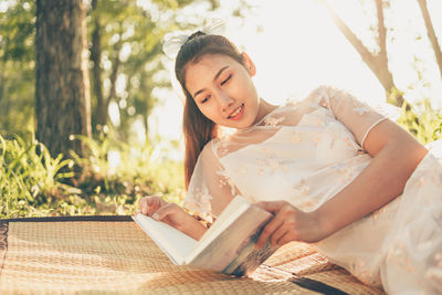 Young woman reading book outdoors