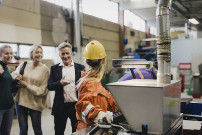 Senior businessman and family talking with female worker in factory