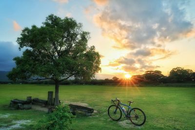 Bicycle on field against sky during sunset