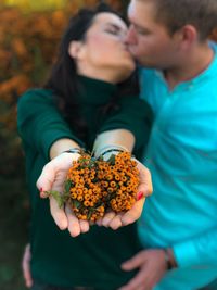Couple kissing outdoors while holding berries outdoors