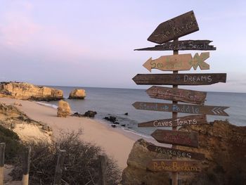 Information sign on beach against sky