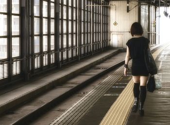 Rear view of woman walking on railroad station platform