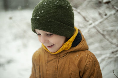 Portrait preschooler boy wearing hat during winter, let it snow. stylish winter clothes for children