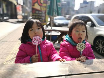 Two girls eating lollipops outdoors