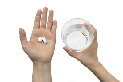 Close-up of hand holding glass over white background