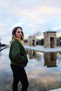 Portrait of smiling young woman standing against sky