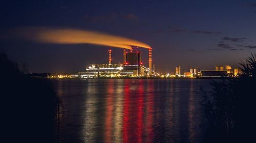 Illuminated factory against sky at night